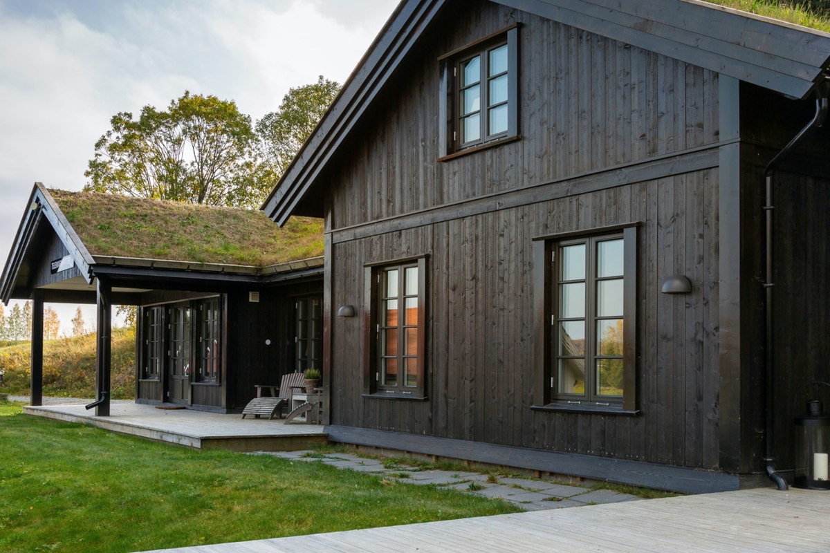 En brun hytte med grønt gress på taket