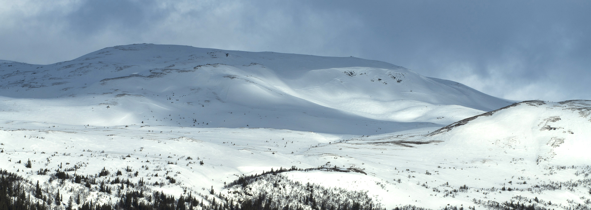Et snødekt landskap med fjelltopper i bakgrunnen